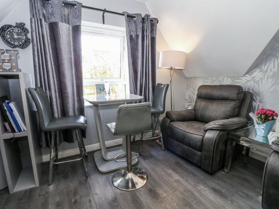 A living room with a chair and table at 24 Wilmslow Court in Wilmslow