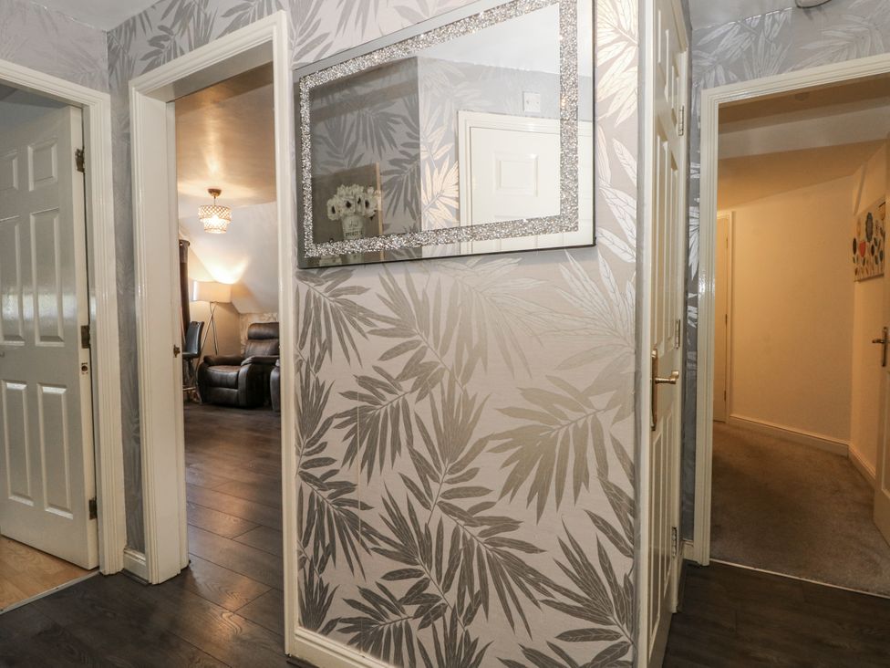 A hallway with doors and a mirror at 24 Wilmslow Court, Wilmslow