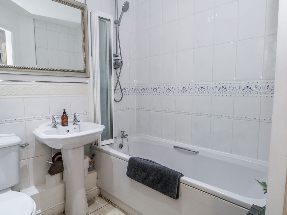A bathroom with a bathtub, sink, and toilet at 24 Wilmslow Court in Wilmslow
