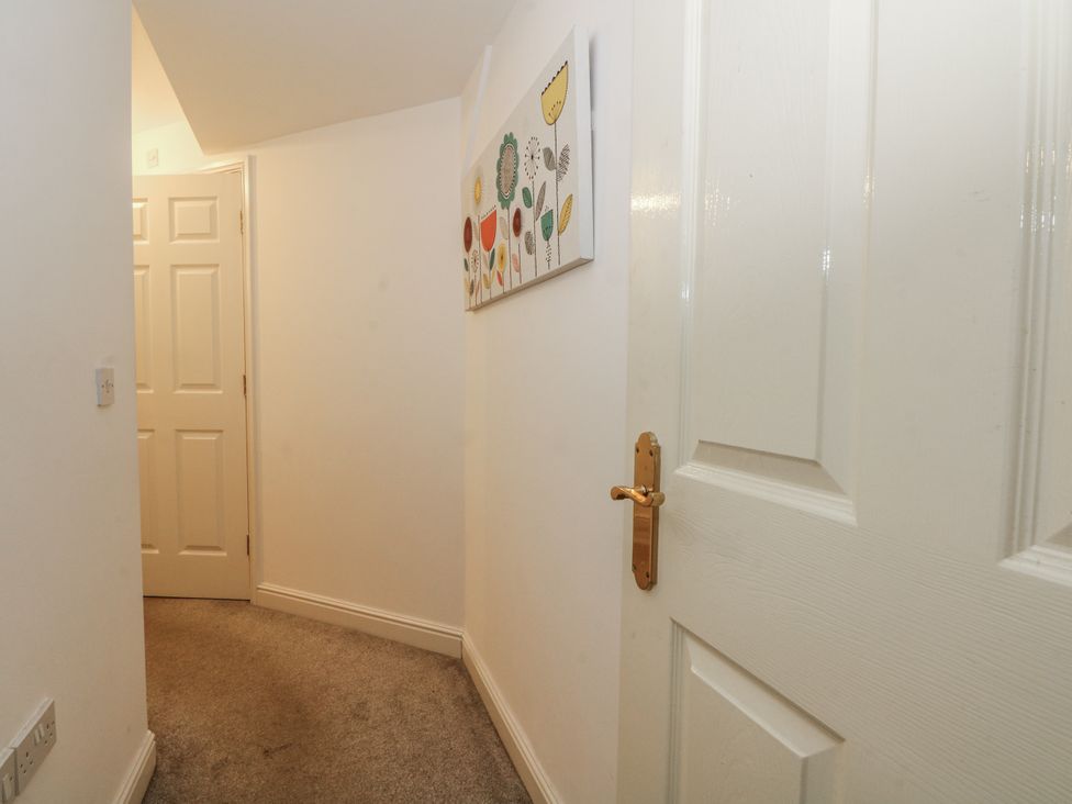 A hallway with doors and wall art at 24 Wilmslow Court in Wilmslow