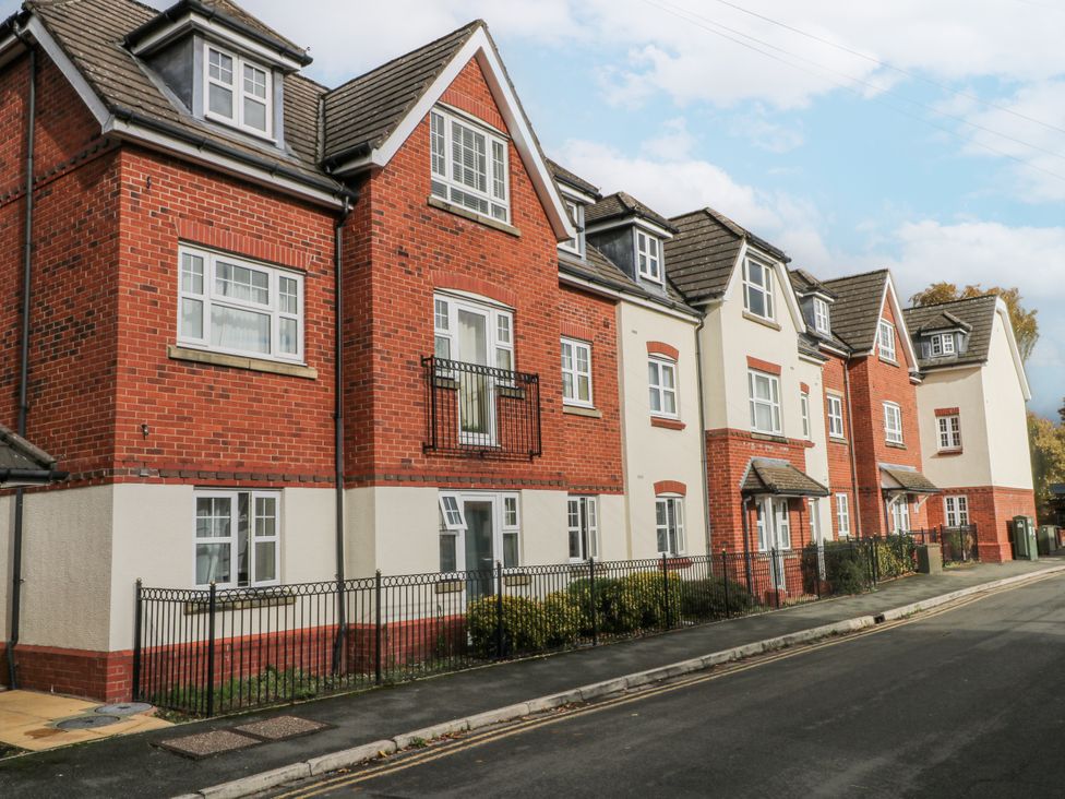 A red brick building with balconies along a street at 24 Wilmslow Court in Wilmslow