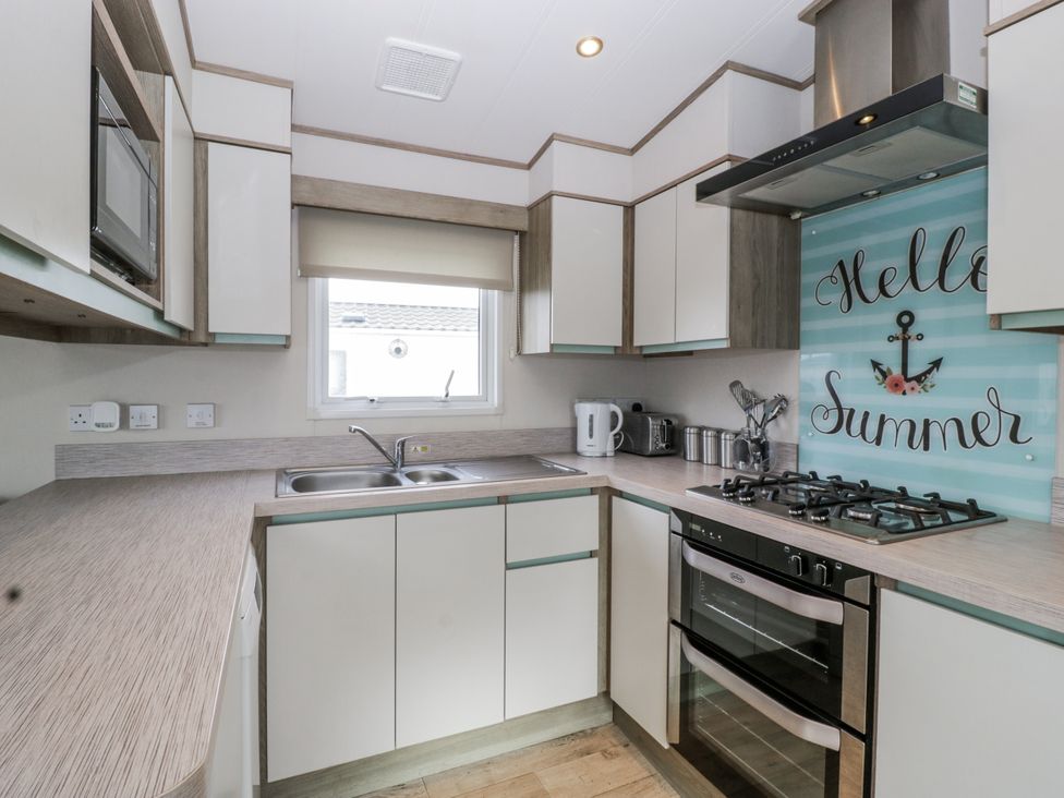 A kitchen with cabinets and appliances at Caravan - 2 Bayside in Watchet