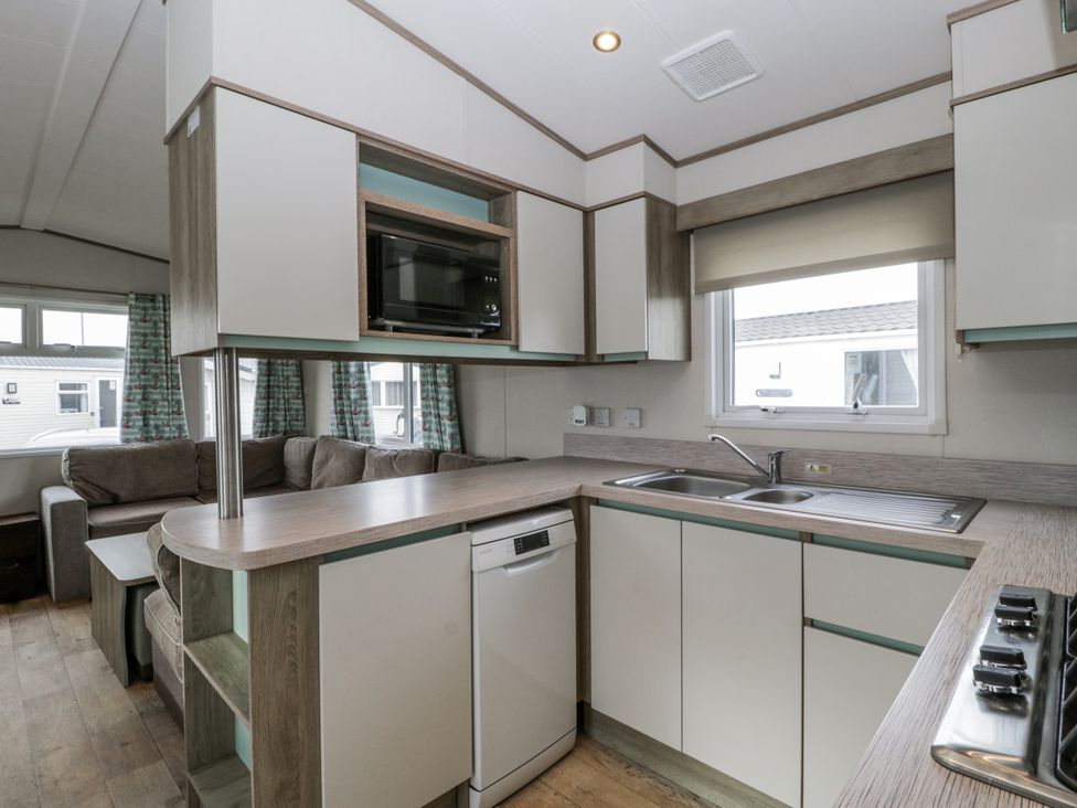A kitchen with a sink, dishwasher, and microwave at Caravan - 2 Bayside Watchet