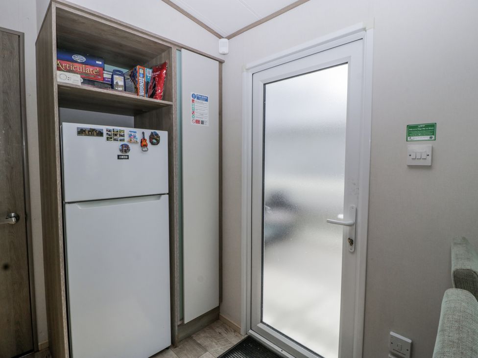 A kitchen with a fridge and door at Caravan - 2 Bayside Watchet