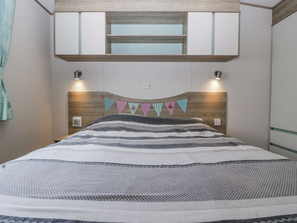 A bedroom with a bed and shelves at Caravan - 2 Bayside in Watchet