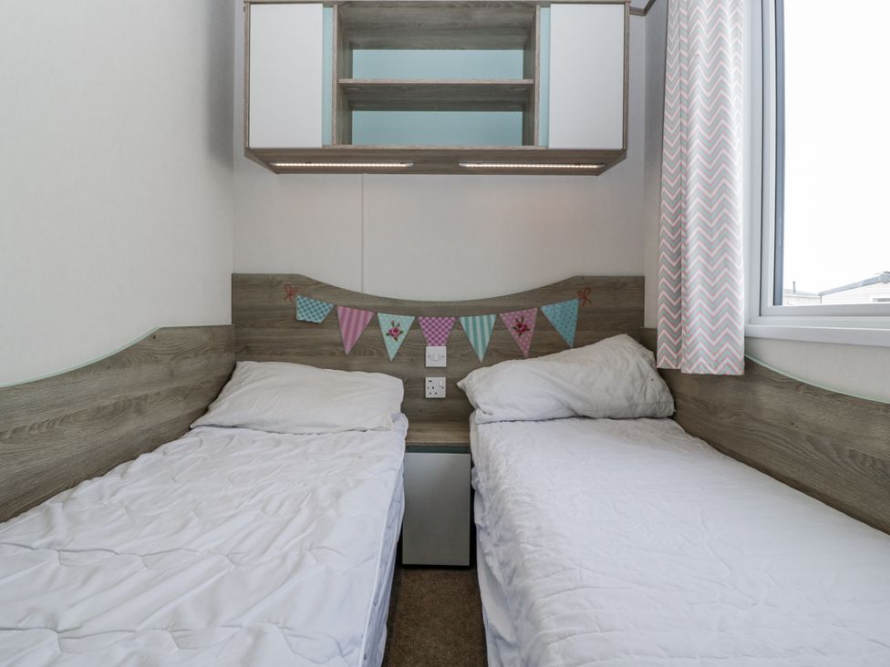 A bedroom with two beds and a shelf at Caravan - 2 Bayside Watchet