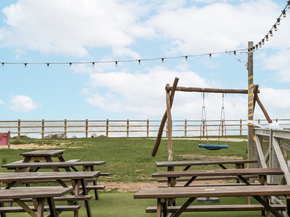 An outdoor area with tables and a swing at Caravan - 2 Bayside in Watchet