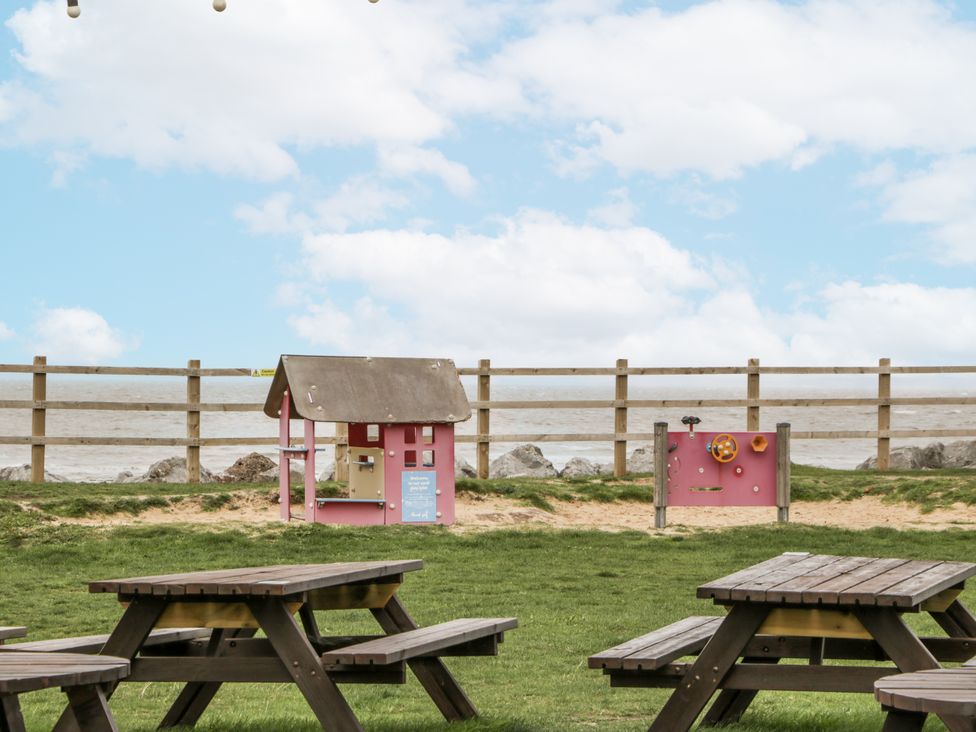 A play area with a pink playhouse and water playstation near picnic tables at Caravan - 2 Bayside Watchet