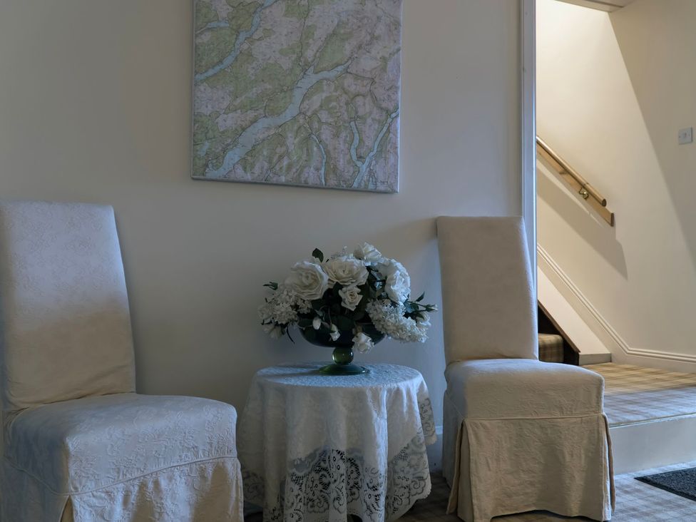 A lobby with chairs and a table holding flowers at Newton Hall in Inveraray