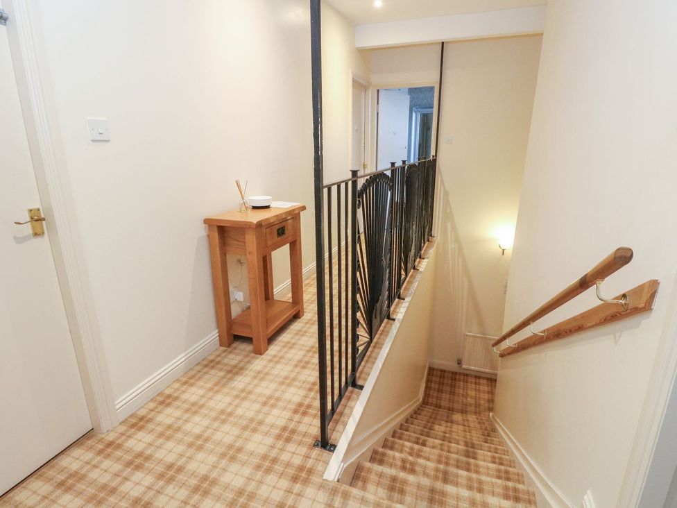 A hallway with a staircase and console table at Newton Hall in Inveraray
