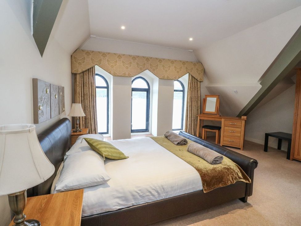 A bedroom with a bed and dressing table at Newton Hall in Inveraray