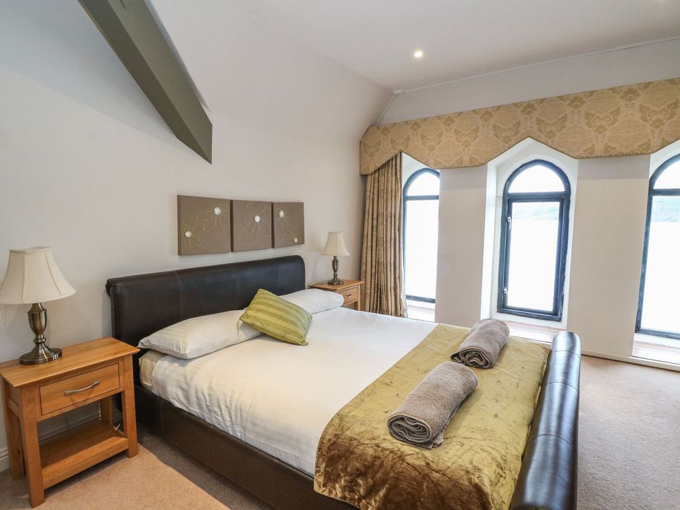 A bedroom with a bed and windows at Newton Hall in Inveraray