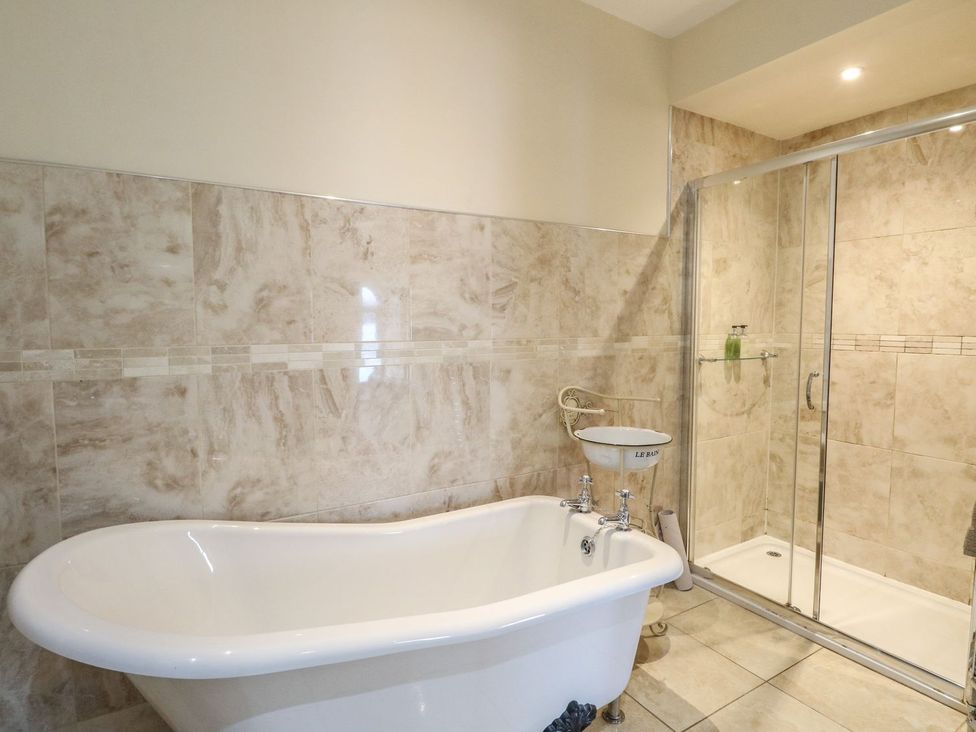 A bathroom with a bathtub, shower, and sink at Newton Hall in Inveraray
