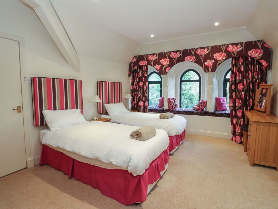 A bedroom with two beds and a window seat at Newton Hall in Inveraray