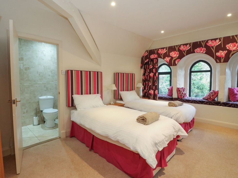 A bedroom with twin beds and a bathroom at Newton Hall in Inveraray