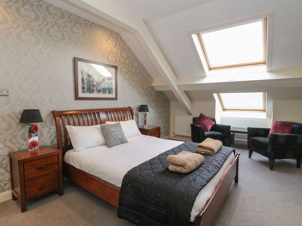 A bedroom with a bed and two chairs at Newton Hall Inveraray