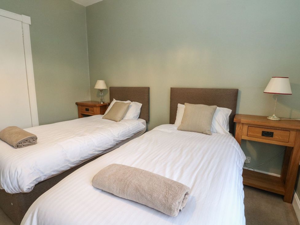 A bedroom with two single beds and a nightstand at Newton Hall in Inveraray
