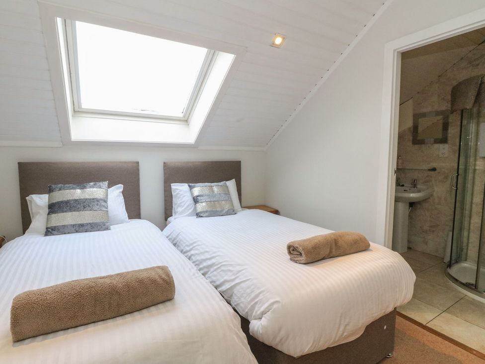 A bedroom with two beds and an en suite bathroom at Newton Hall in Inveraray