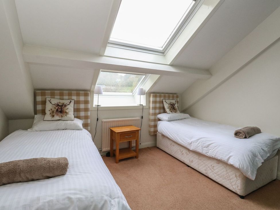 A bedroom with two beds and a table at Newton Hall Inveraray