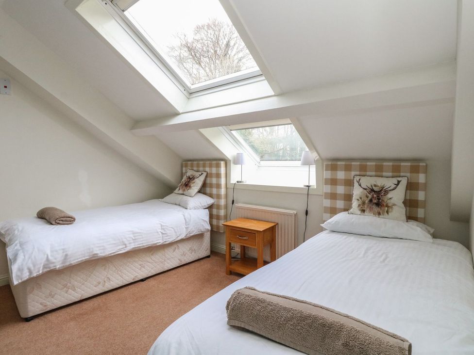 A bedroom with two beds and a bedside table at Newton Hall in Inveraray