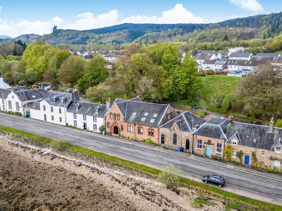 A cluster of houses along a road near trees at Newton Hall in Inveraray