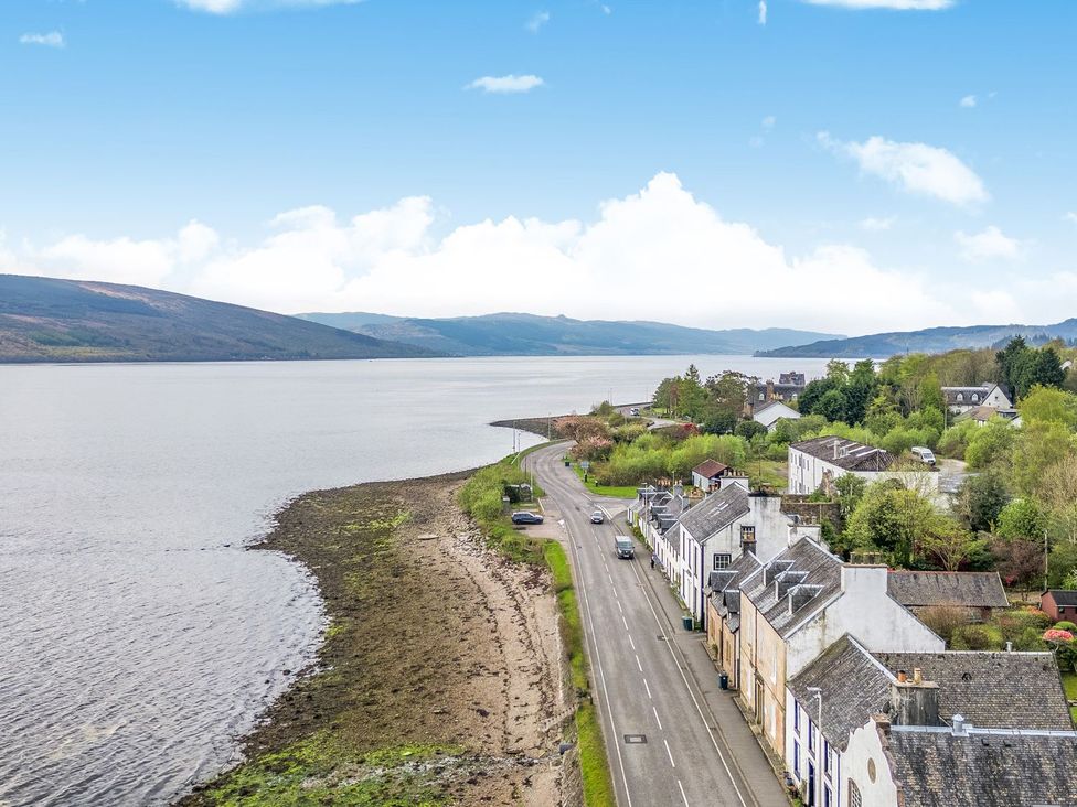 A view of a waterfront with houses and a road at Newton Hall Inveraray