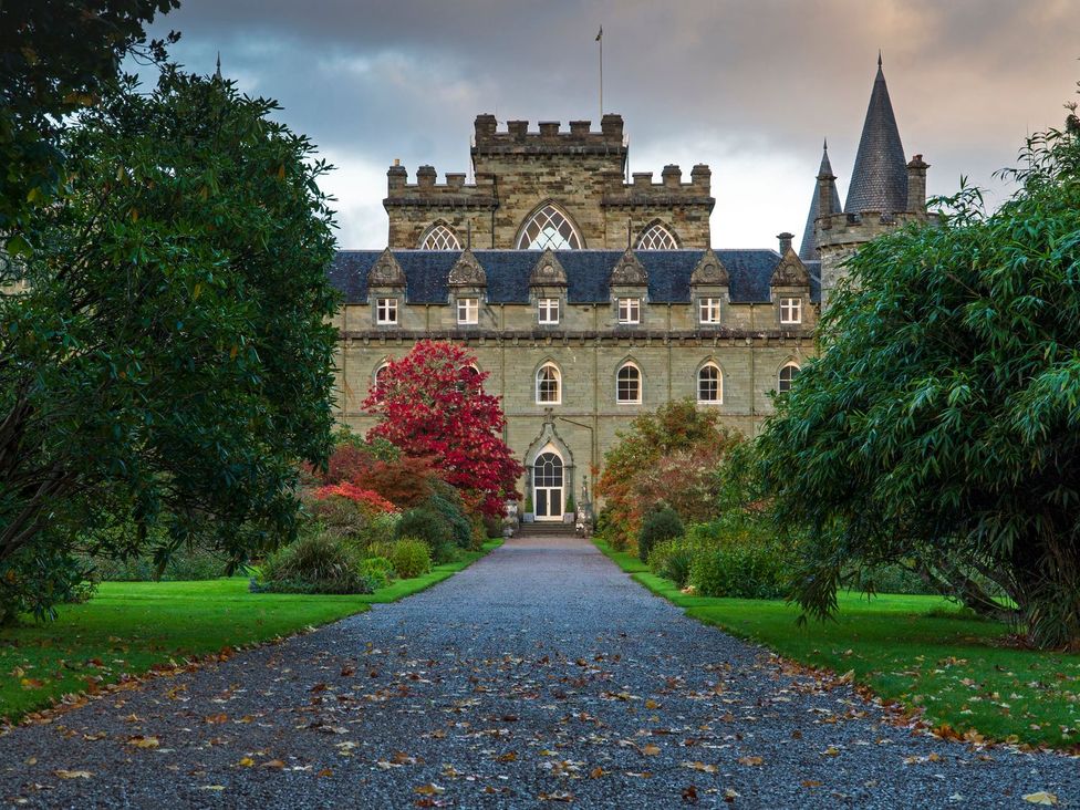 A castle entrance with a pathway surrounded by trees at Newton Hall in Inveraray