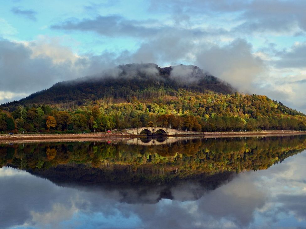 A mountain with a bridge over a lake at Newton Hall in Inveraray