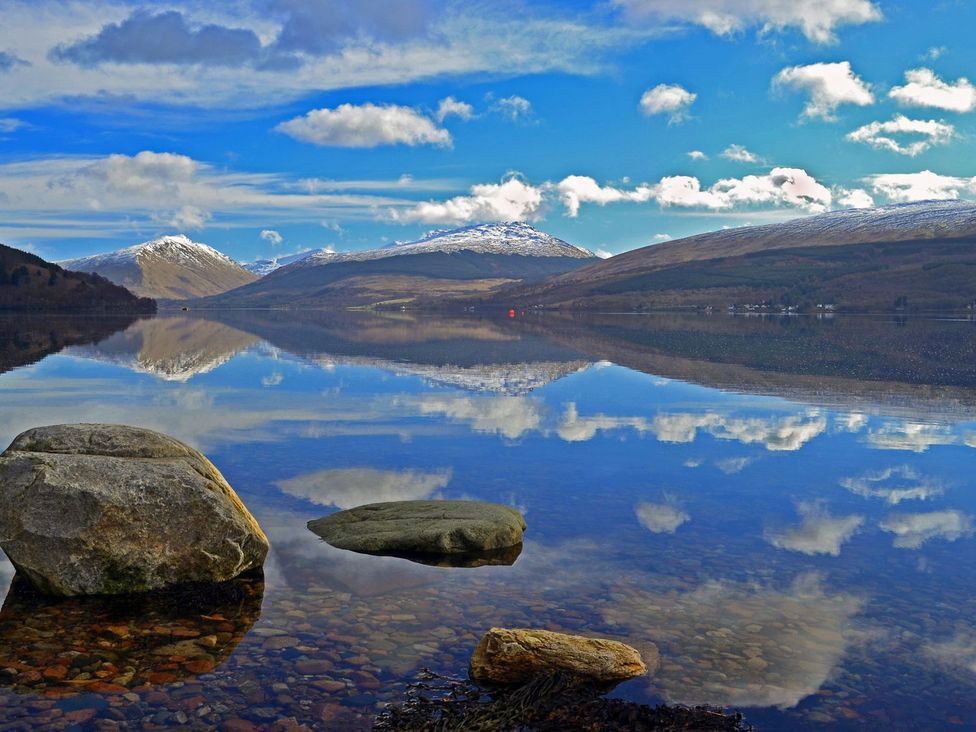 A scenic view of mountains and water with reflections at Newton Hall in Inveraray