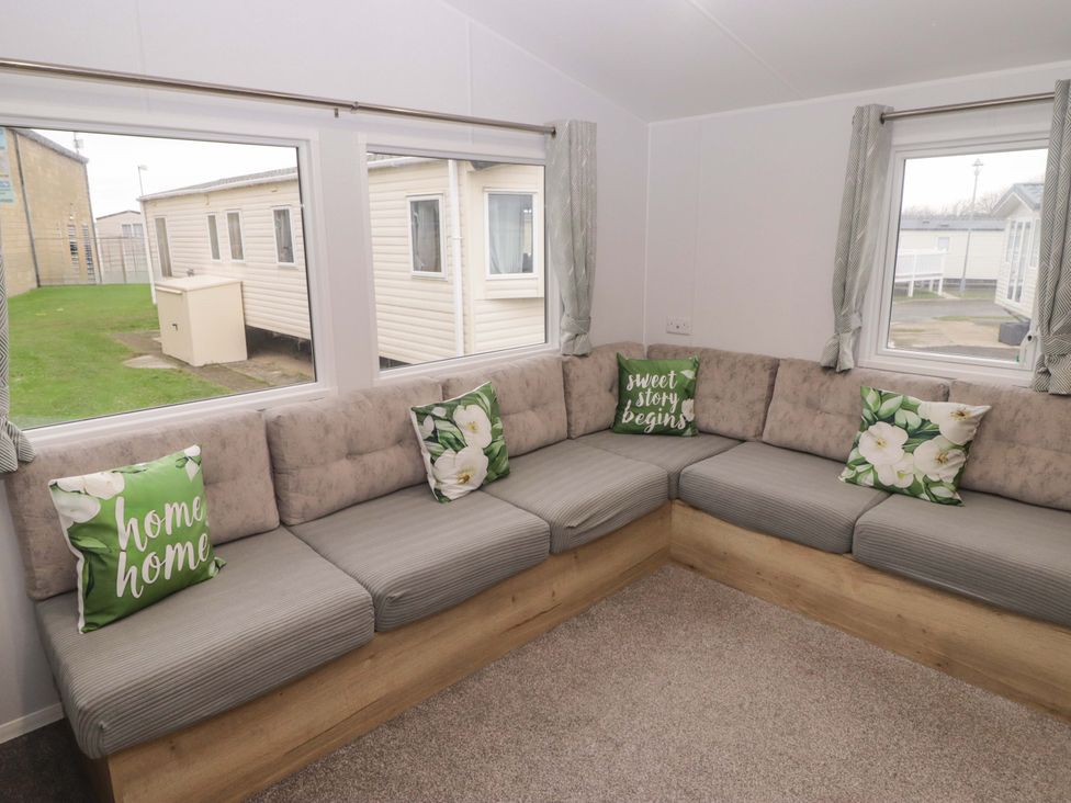 A living room with a corner sofa and cushions at 47 Chestnut Road Porthcawl