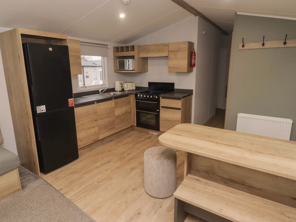 A kitchen with a stove, fridge, and cabinets at 47 Chestnut Road in Porthcawl