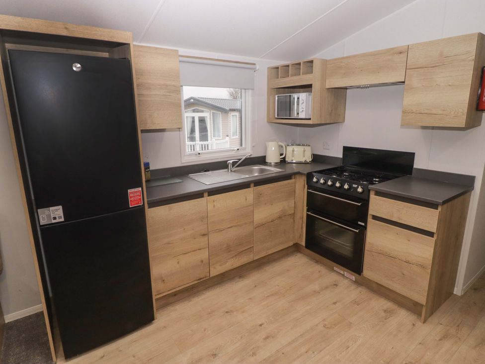 A kitchen with a refrigerator, sink, and oven at 47 Chestnut Road Porthcawl