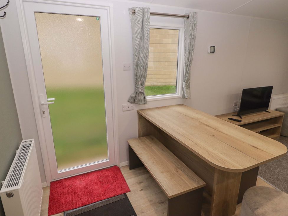 A dining area with a table and bench at 47 Chestnut Road Porthcawl