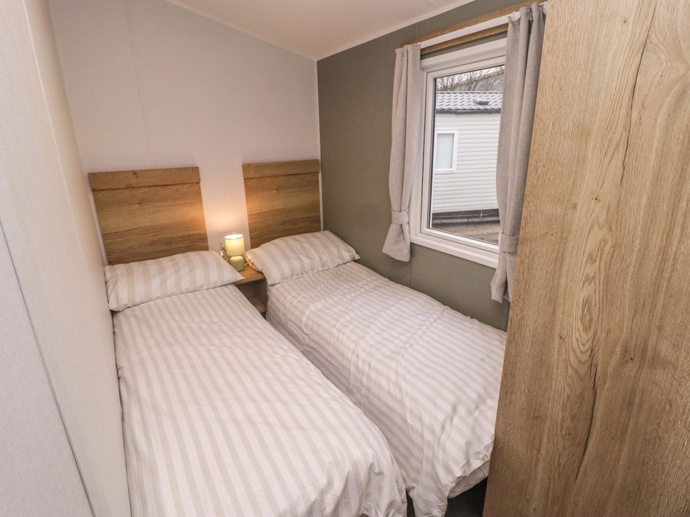 A bedroom with twin beds and a window at 47 Chestnut Road in Porthcawl