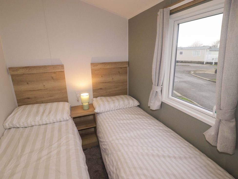 A bedroom with two beds and a lamp at 47 Chestnut Road in Porthcawl