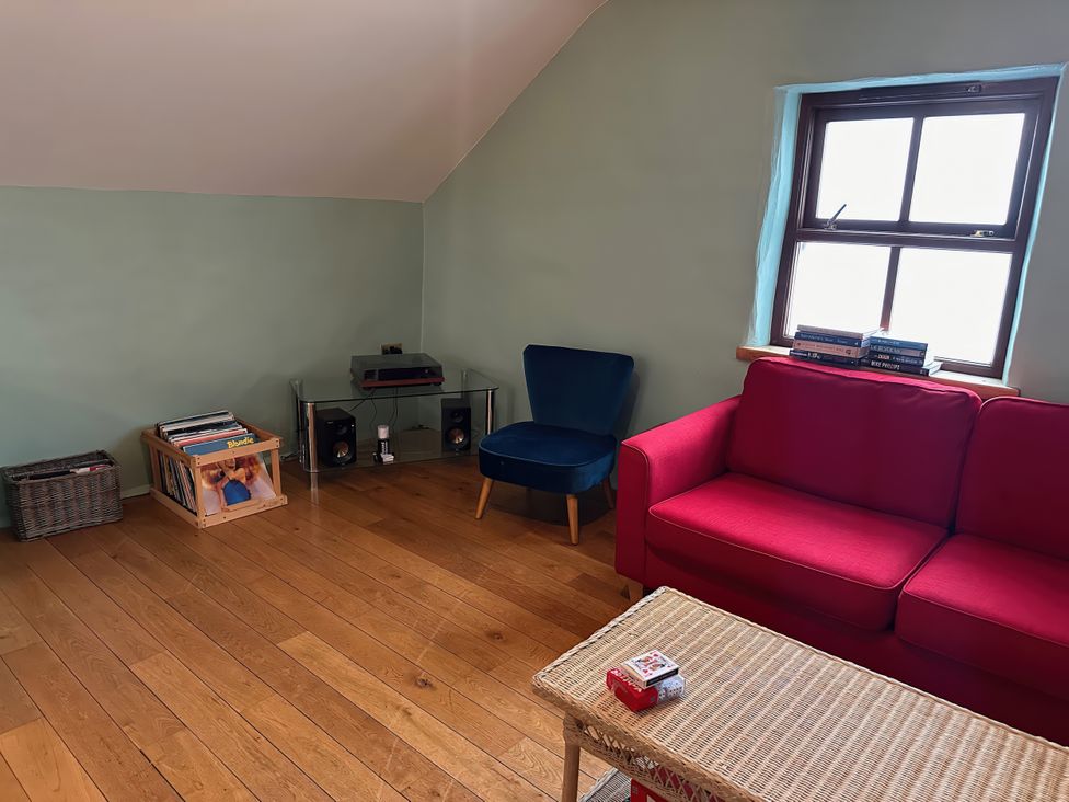 A living room with a red sofa and blue armchair at Jabajak in Whitland