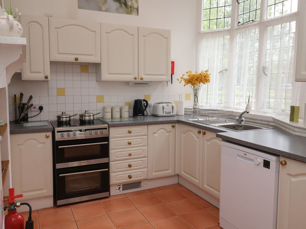 A kitchen with stove, sink, and cupboards at Duke Cottage in Woodbridge