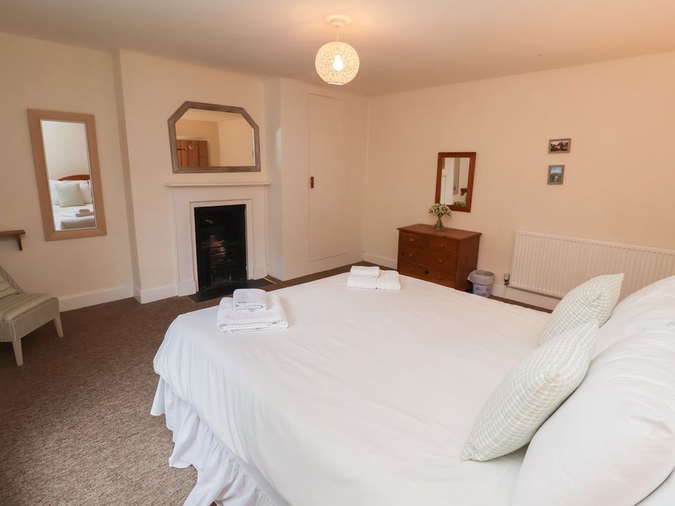 A bedroom with a bed and a mirror at Duke Cottage in Woodbridge