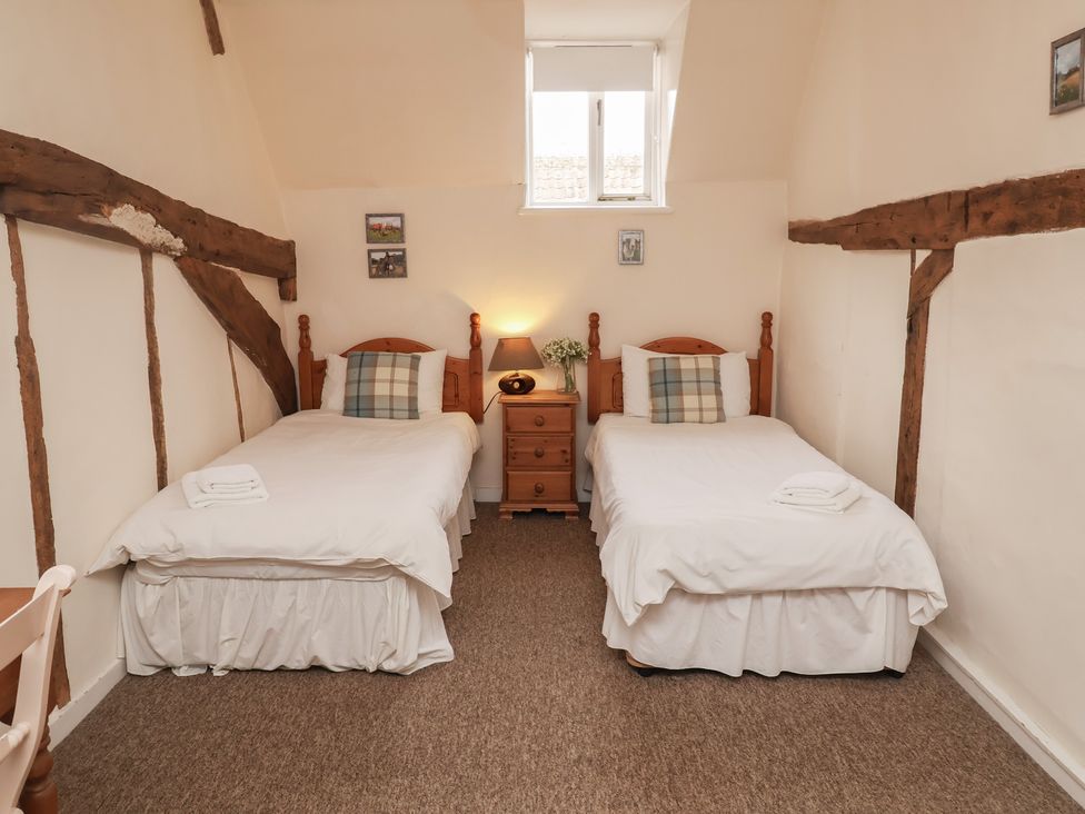 A bedroom with two beds and a bedside table at Duke Cottage in Woodbridge