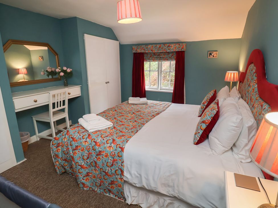 A bedroom with a bed and a desk at Duchess Cottage in Woodbridge