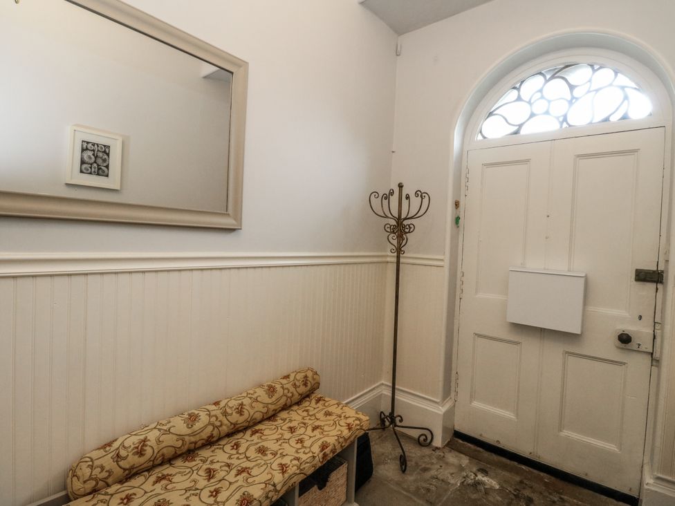 A hallway with a mirror, bench, and coat rack at Rowan Tree House Brechin