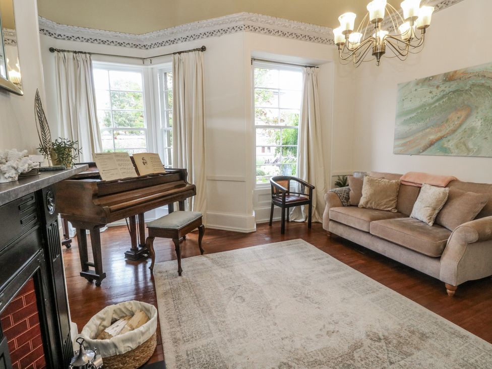 A living room with a piano and sofa at Rowan Tree House in Brechin