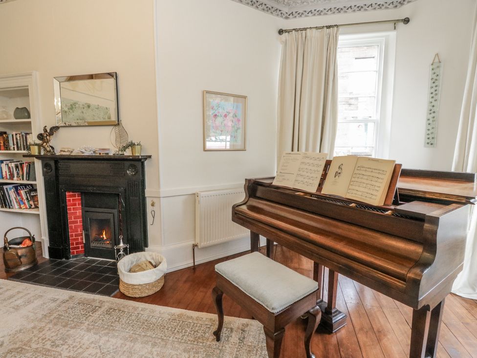 A living room with a piano and a fireplace at Rowan Tree House in Brechin