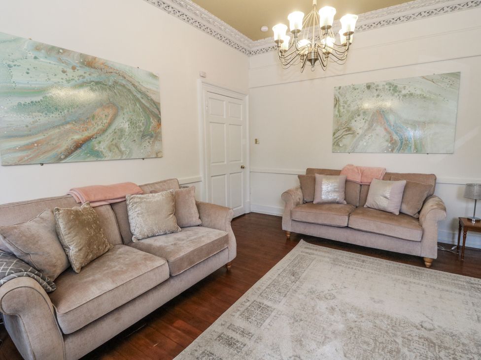 A living room with sofas and paintings at Rowan Tree House in Brechin