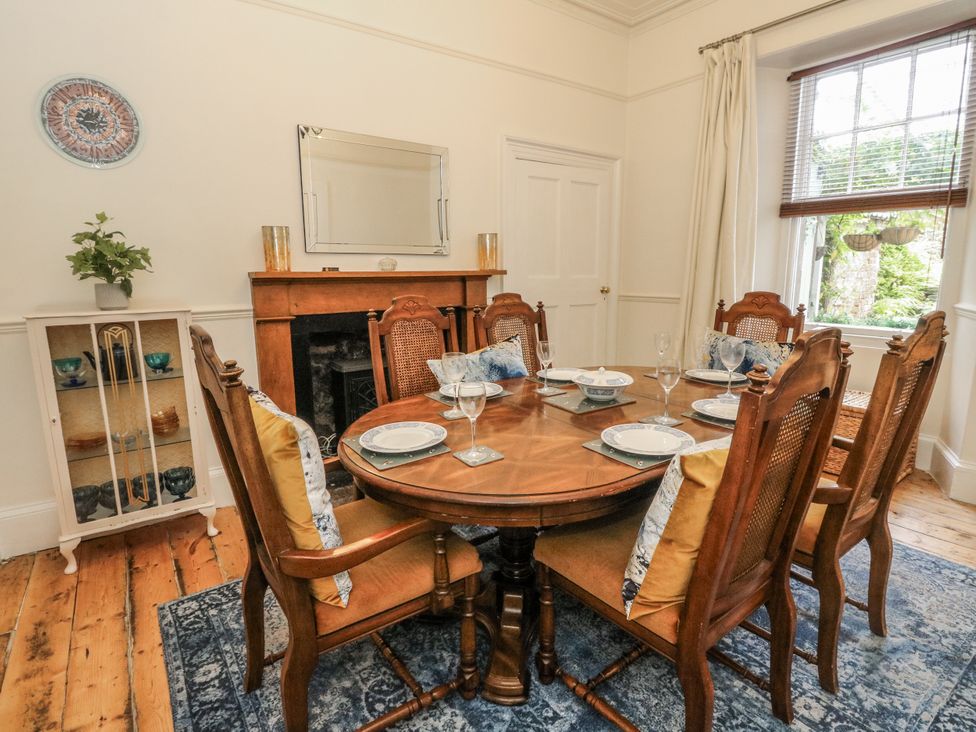 A dining room with a round table set for dinner at Rowan Tree House in Brechin