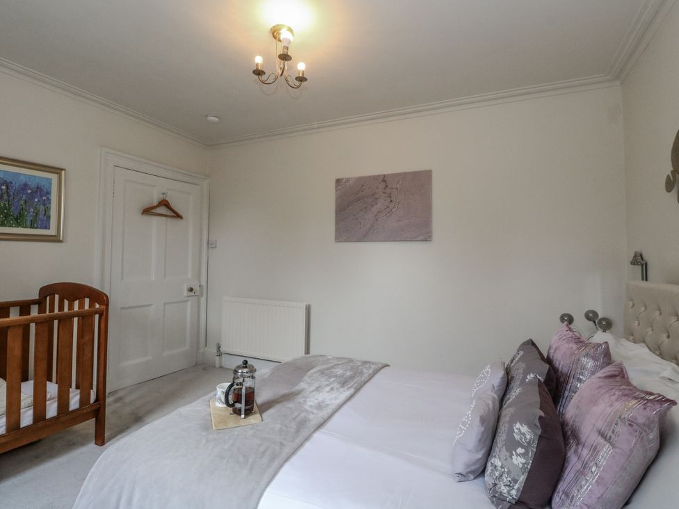 A bedroom with a bed and a crib at Rowan Tree House in Brechin