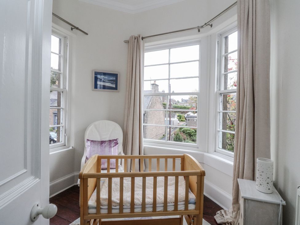 A nursery with a crib and windows at Rowan Tree House Brechin