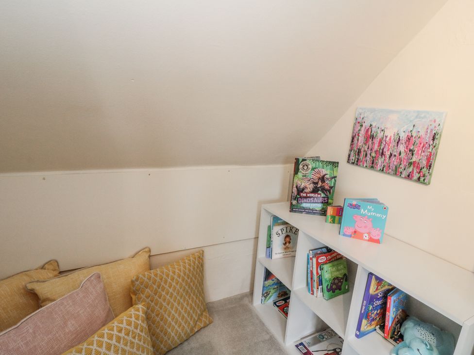 A snug with cushions and a bookshelf filled with children's books at Rowan Tree House Brechin