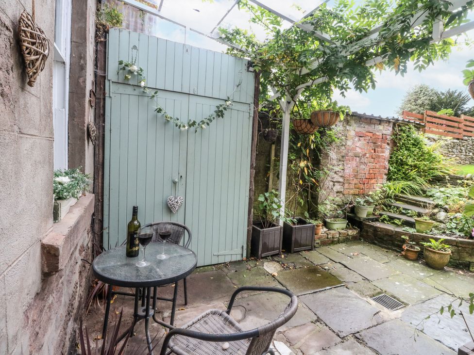A garden with a table and chairs and a green door at Rowan Tree House Brechin