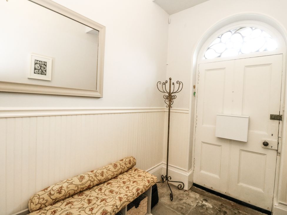 A hallway with a mirror, bench, and coat rack at Rowan Tree House, Brechin